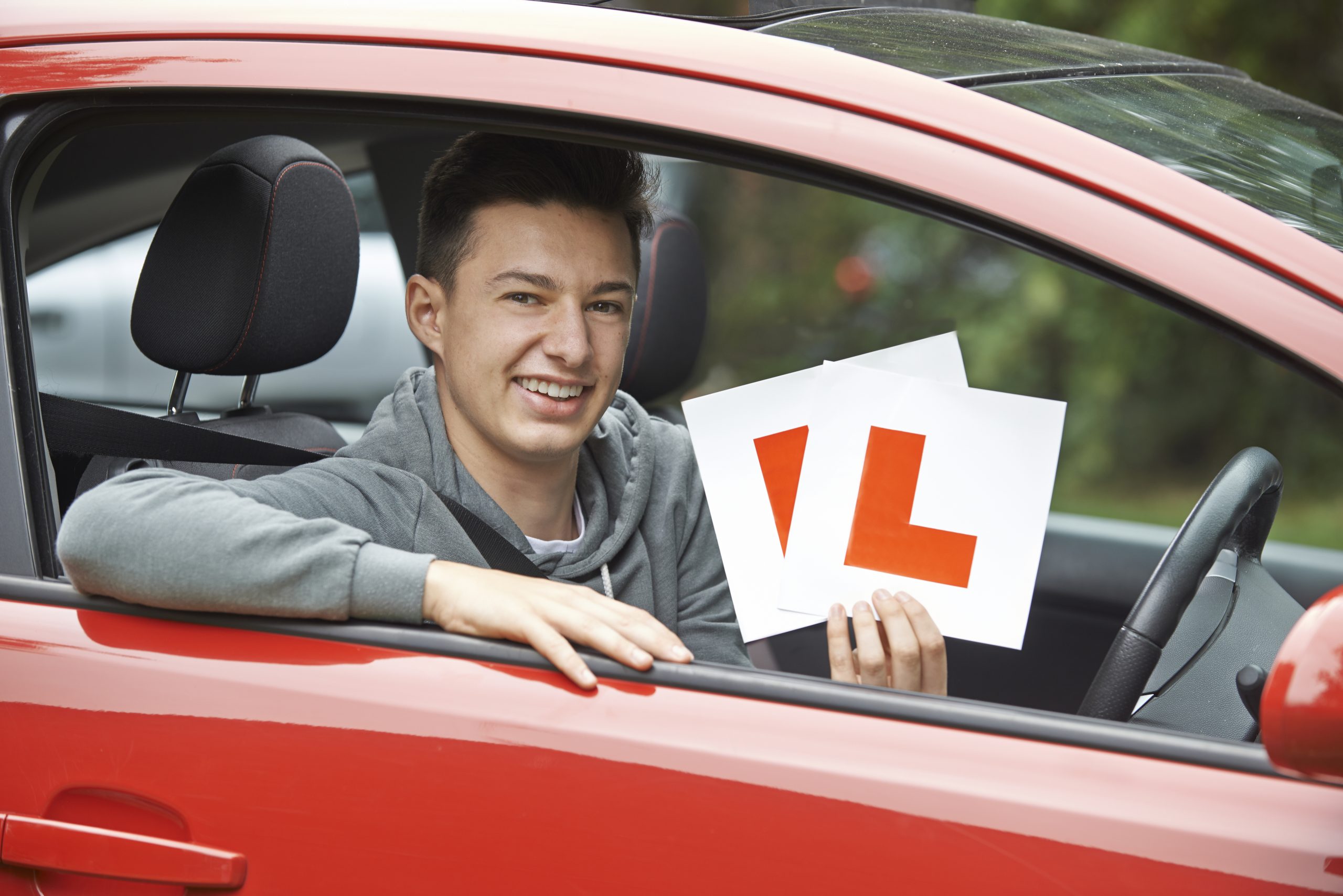 smiling boy with L signs on his car