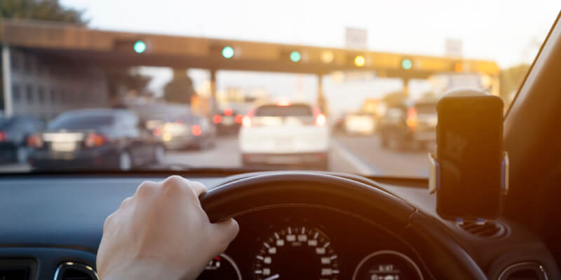 Hand holding steering wheel in place whilst in a traffic jam