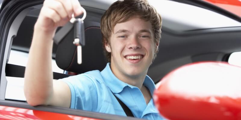 Boy holding up keys and smiling in car