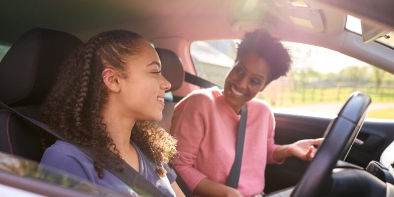 Two women in car smiling at each other